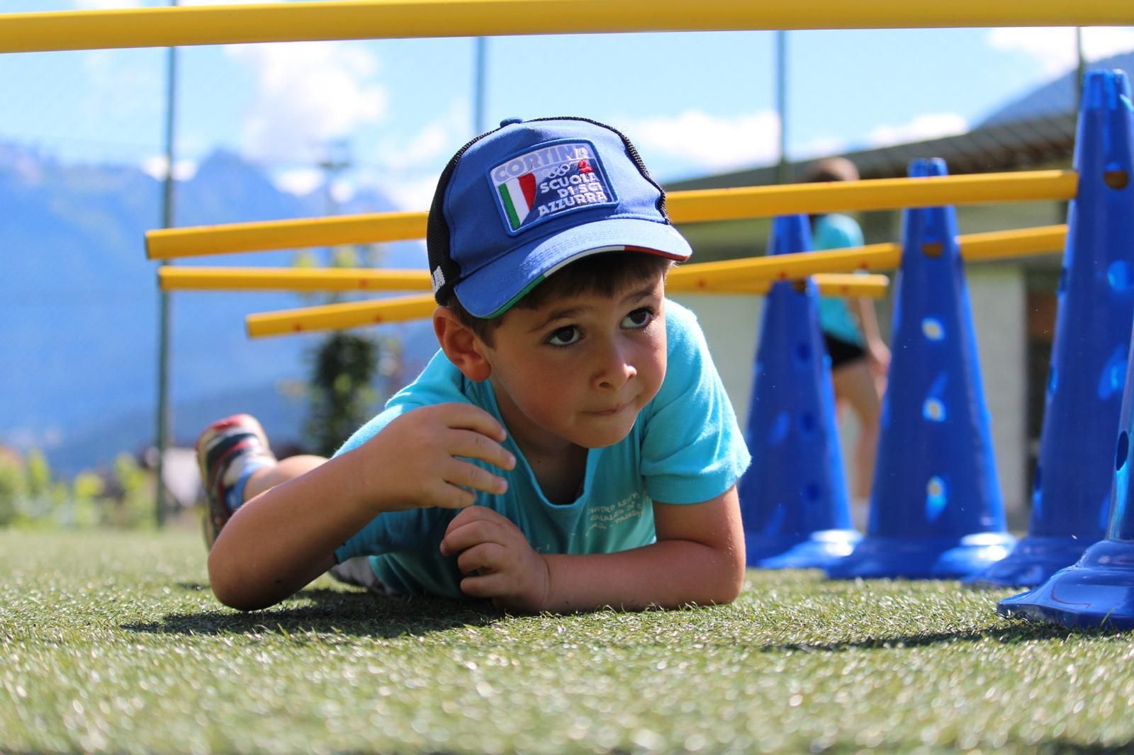 Un ragazzino che indossa un cappello blu è sdraiato sull'erba.