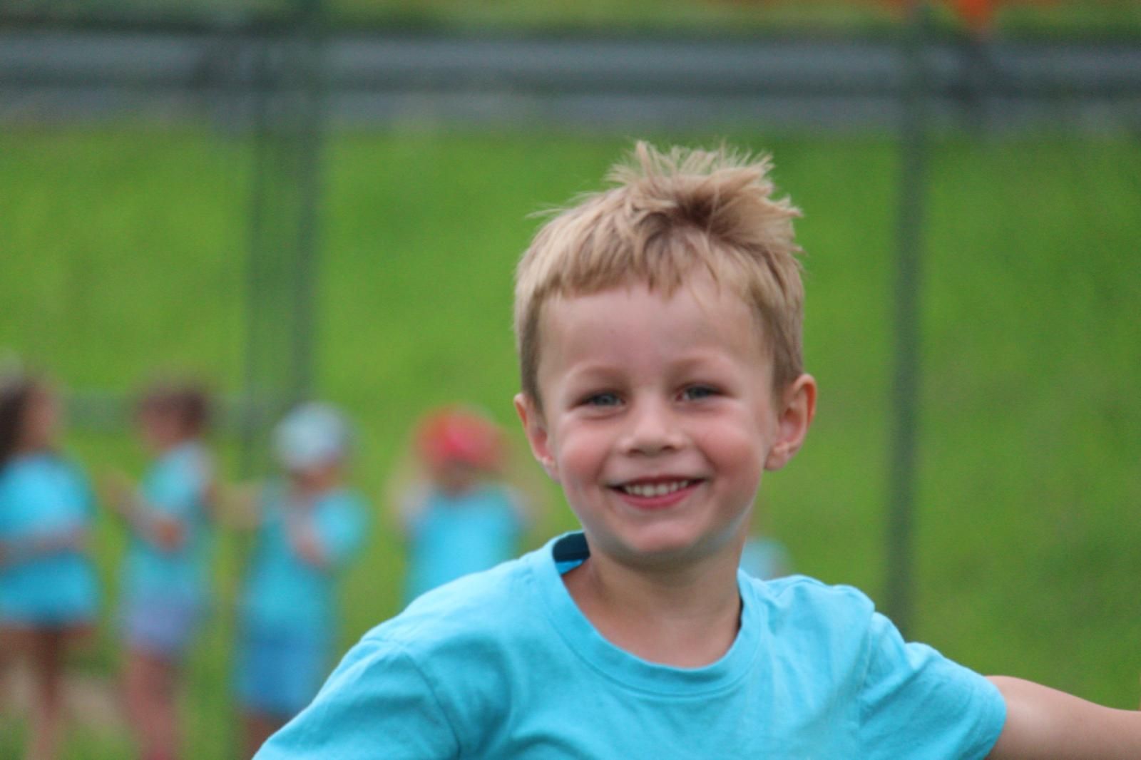 Un ragazzino con una maglietta blu sorride alla telecamera.