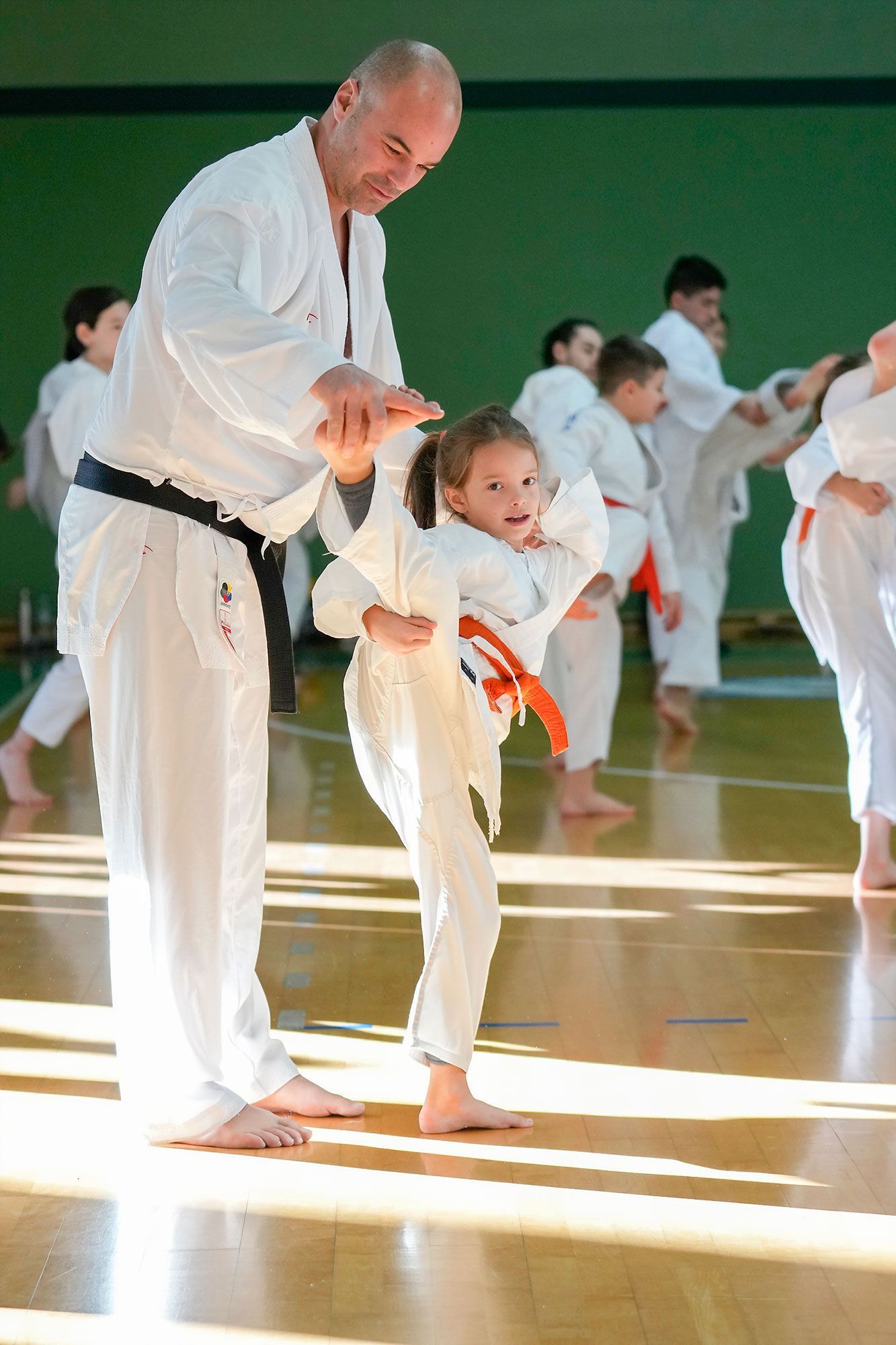 Un uomo insegna a una bambina come fare karate in palestra.