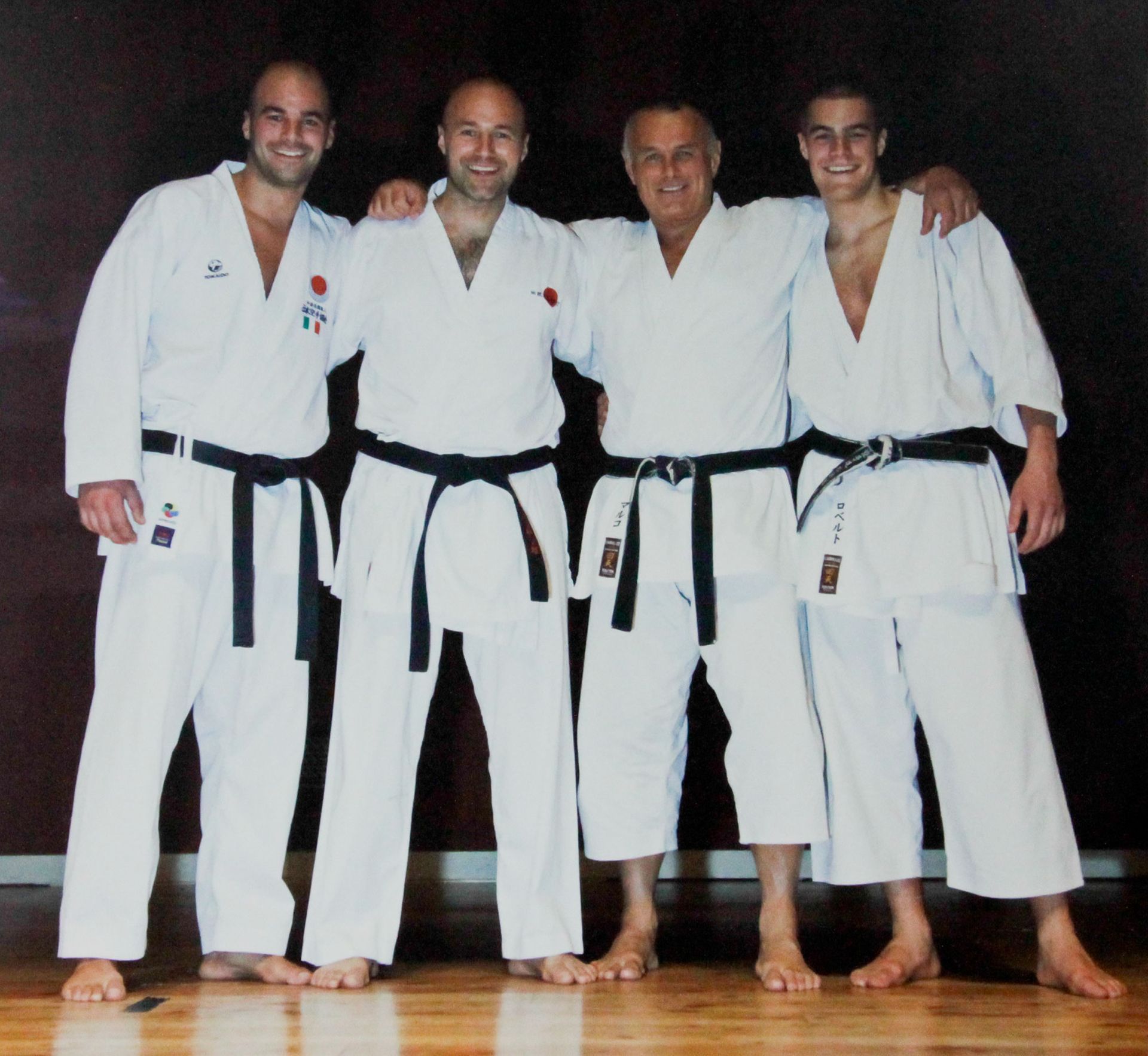 Quattro uomini in uniforme bianca da karate posano per una foto