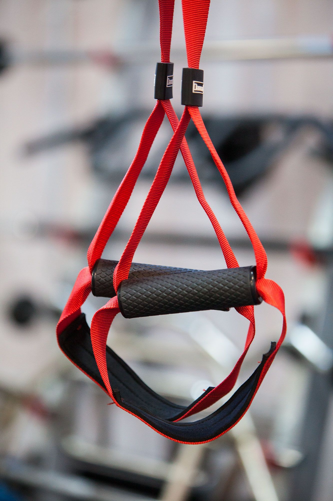 Una cinghia rossa con una maniglia nera è appesa a una barra in una palestra