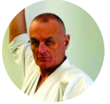 Un uomo con indosso un'uniforme bianca da karate è in piedi in cerchio.