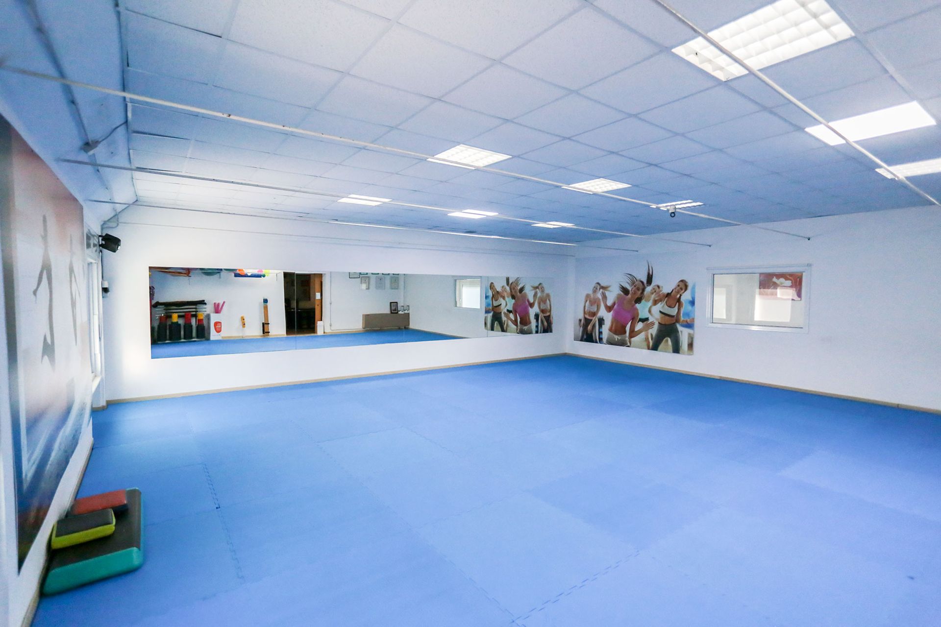 Una palestra vuota con un tappetino blu e un grande specchio.