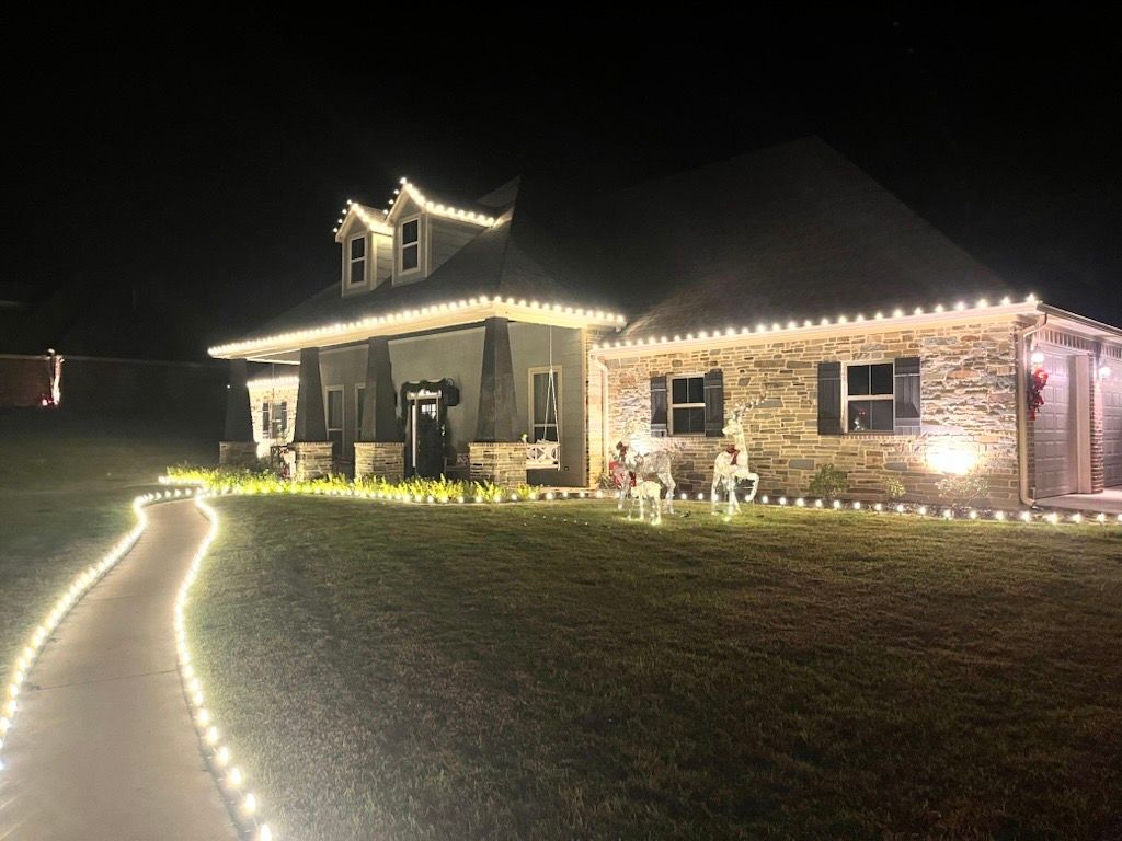 House decorated with white Christmas lights on the roof and walkway, glowing at night.