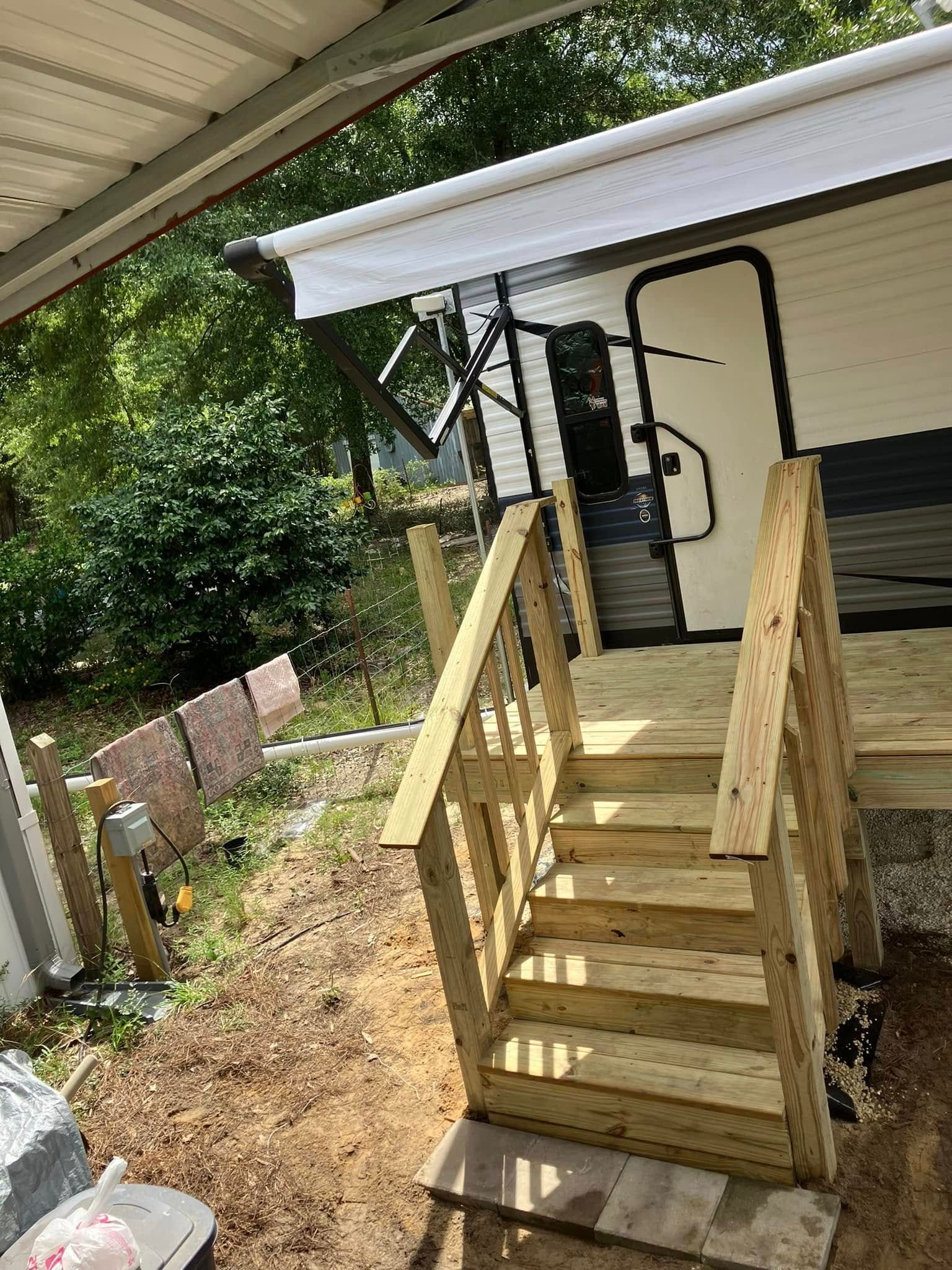 Wooden stairs leading up to a trailer door under a white awning.