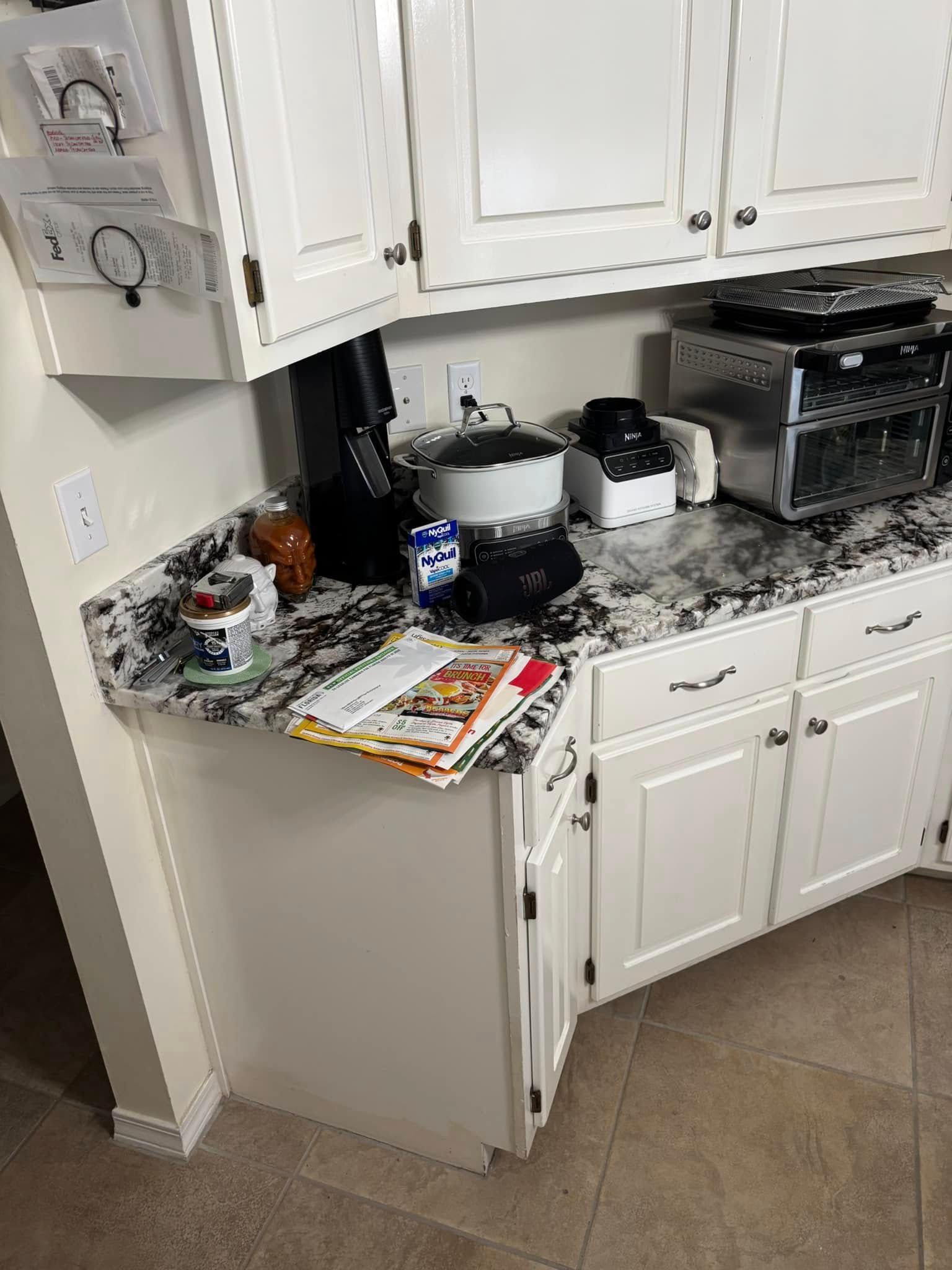 Kitchen counter with white cabinets, granite countertop, and appliances.