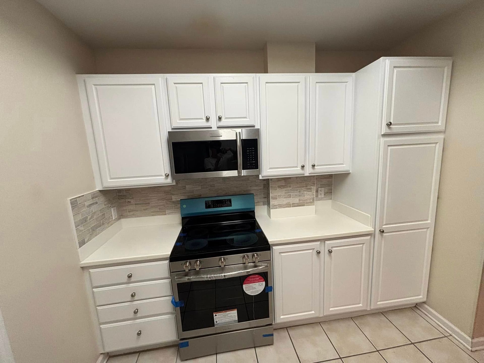 White kitchen cabinets with stainless steel appliances; gas range, microwave.