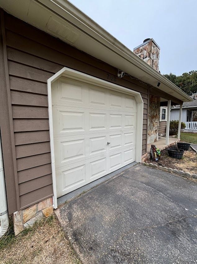 White garage door on a house with brown siding and a driveway.