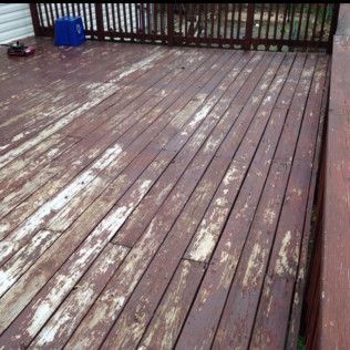 A weathered wooden deck with peeling reddish-brown stain. Faded and worn, shows age and exposure.