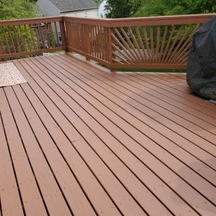Wooden deck with brown railings, overlooking a backyard.