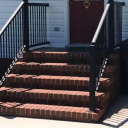 Brick steps leading to a front door with black railings.
