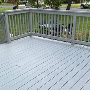 A freshly painted grey deck with a matching railing, overlooking a grassy yard.