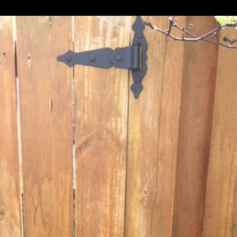 Black decorative hinge on a wooden fence.