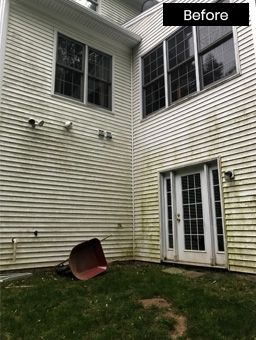 Before: Moldy white siding on a house with windows and a door, an abandoned wheelbarrow on the grass.