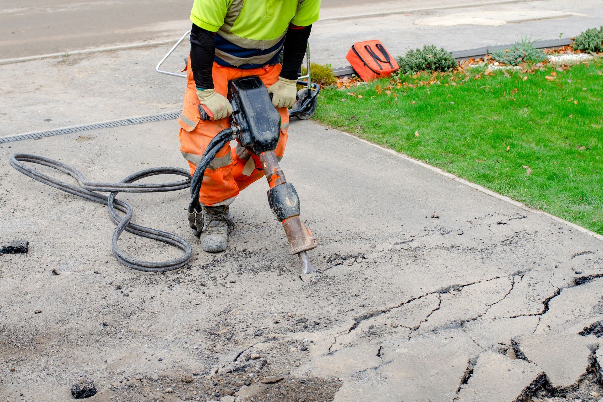 builder breaking asphalt with hydraulic jackhammer