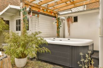 a hot tub is sitting under a pergola in a backyard .