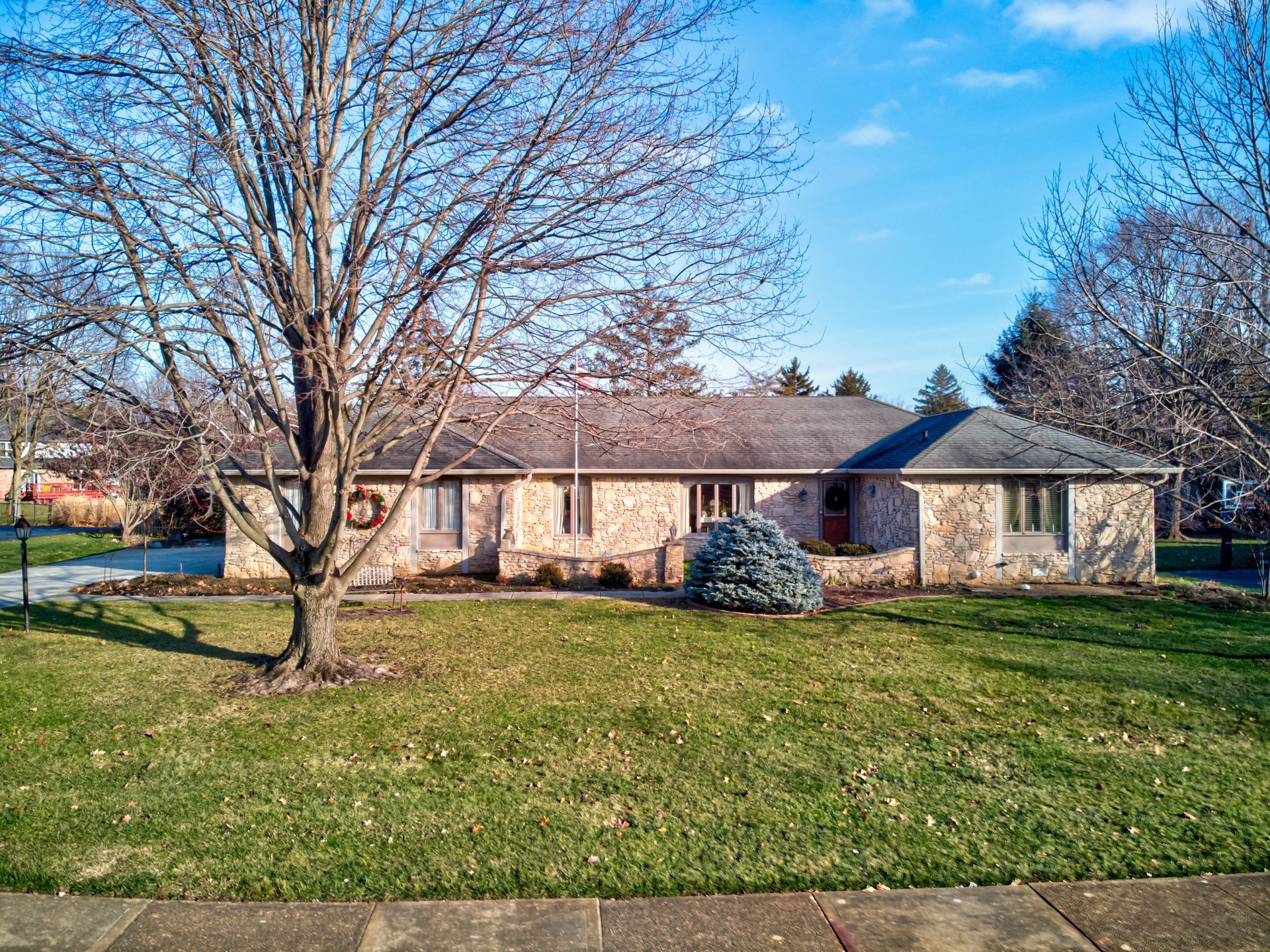 An aerial view of a white house with a gray roof overlooking a body of water