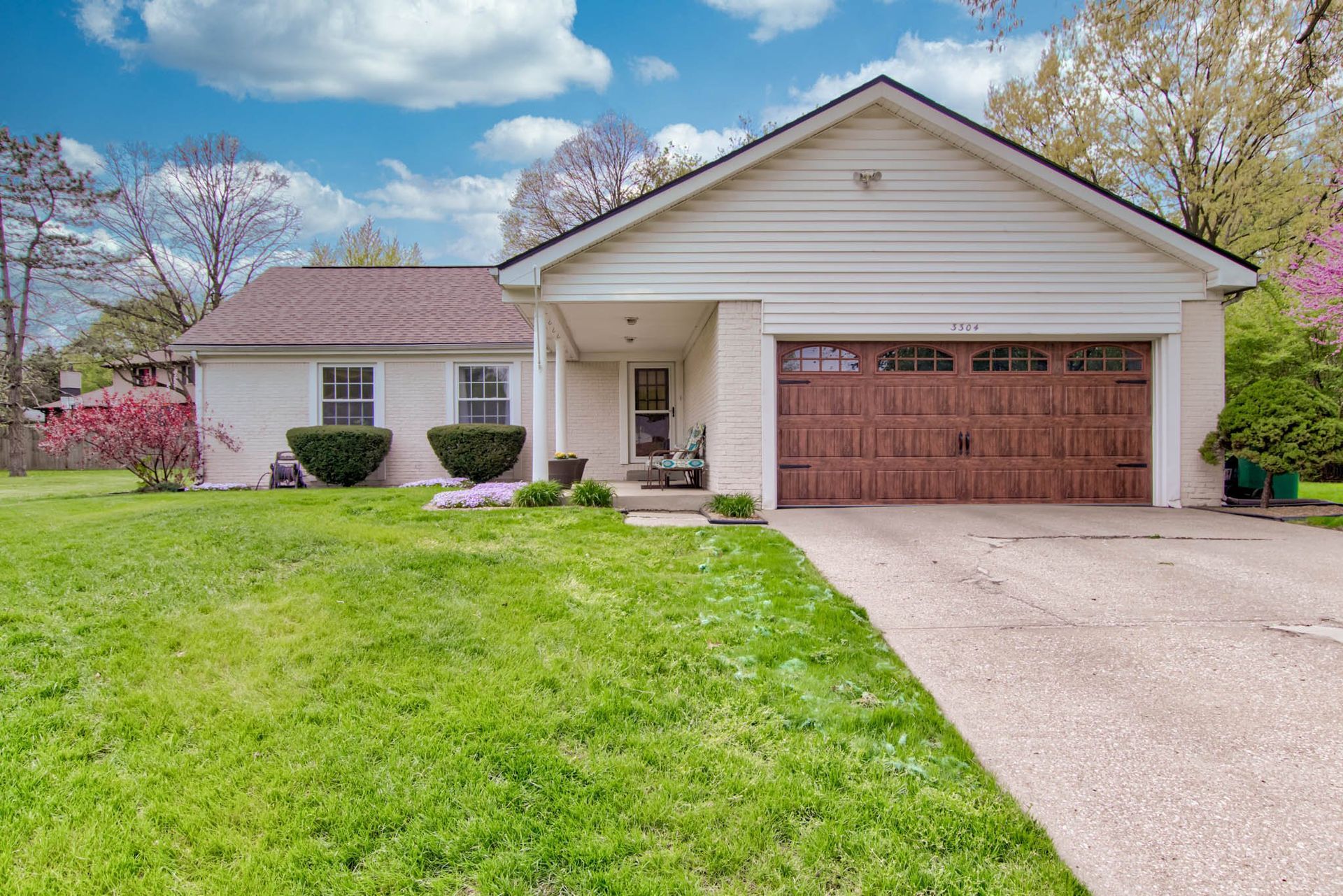 A white house with a large garage and a lush green lawn .