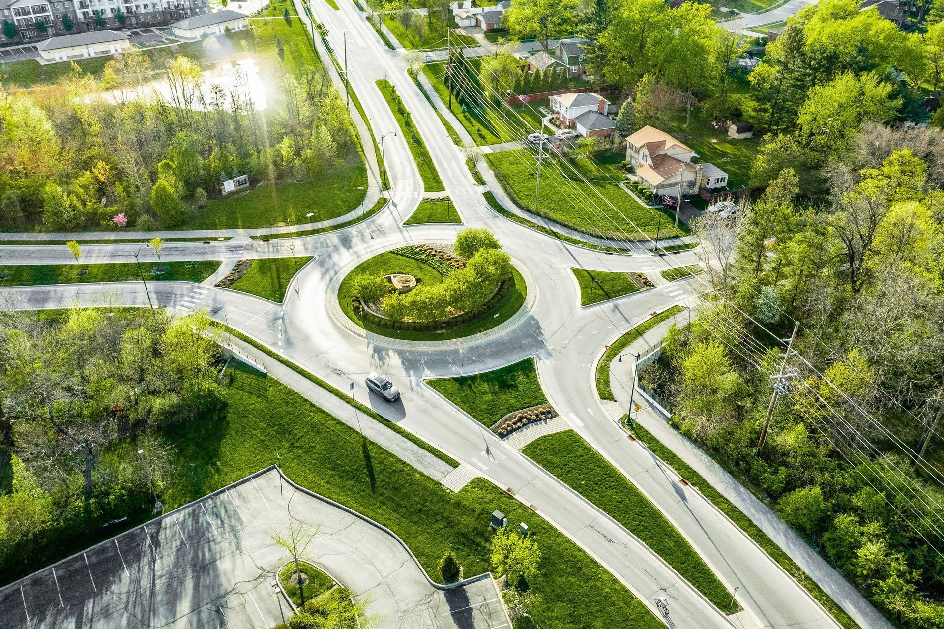 An aerial view of a roundabout surrounded by trees and grass .