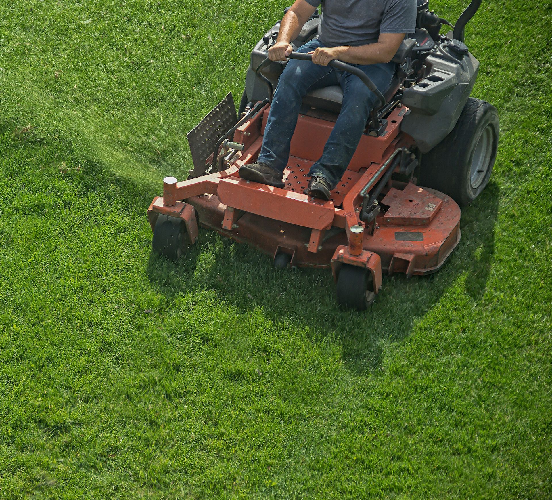 A man is riding a lawn mower on a lush green lawn.