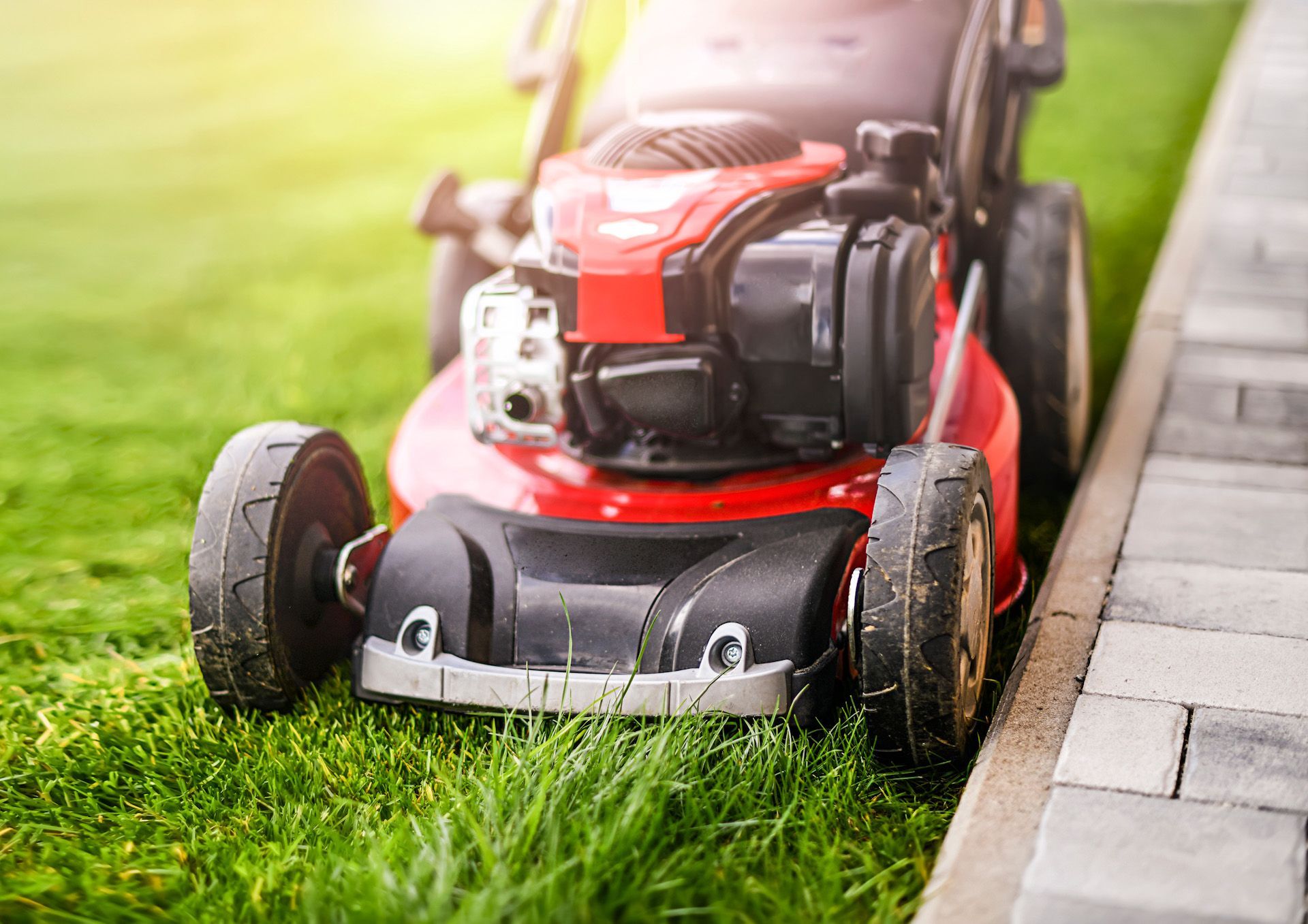 A red lawn mower is cutting a lush green lawn.