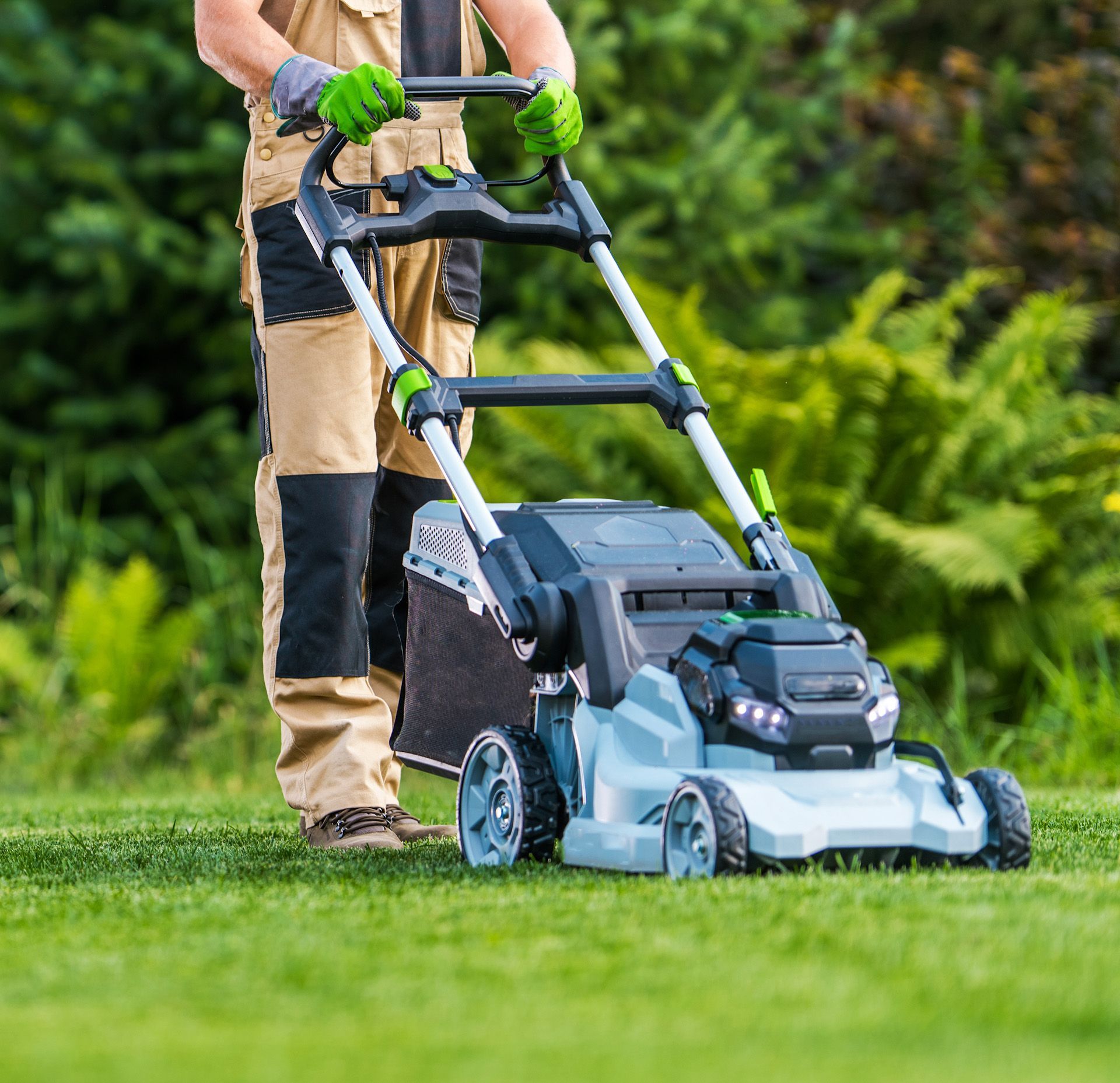 A man is pushing a lawn mower through a lush green field.