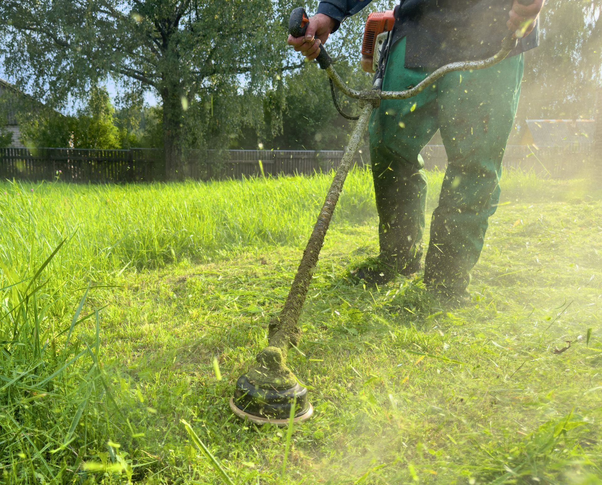 A man is using a lawn mower to cut the grass in a field.