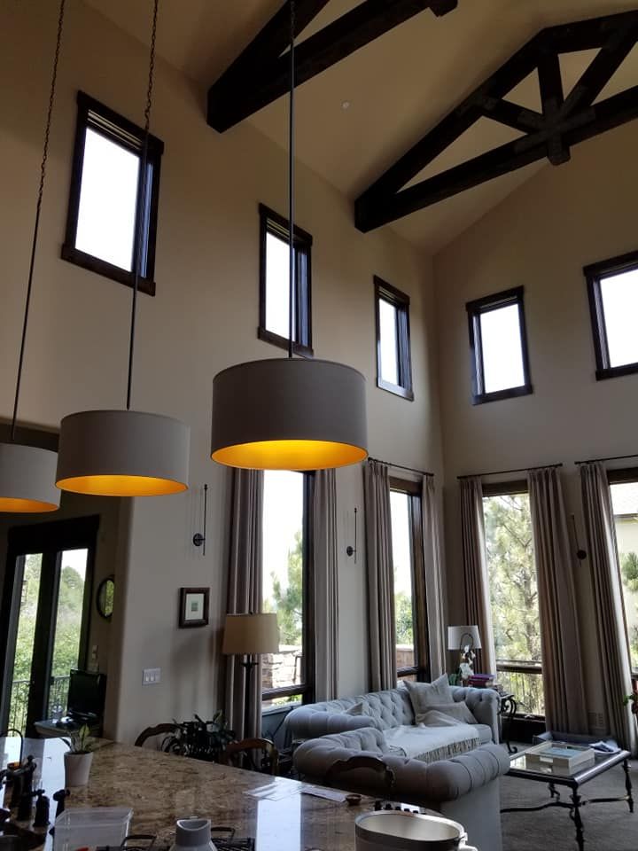 Modern living room with high ceiling, large windows, gray sofa, and hanging pendant lights