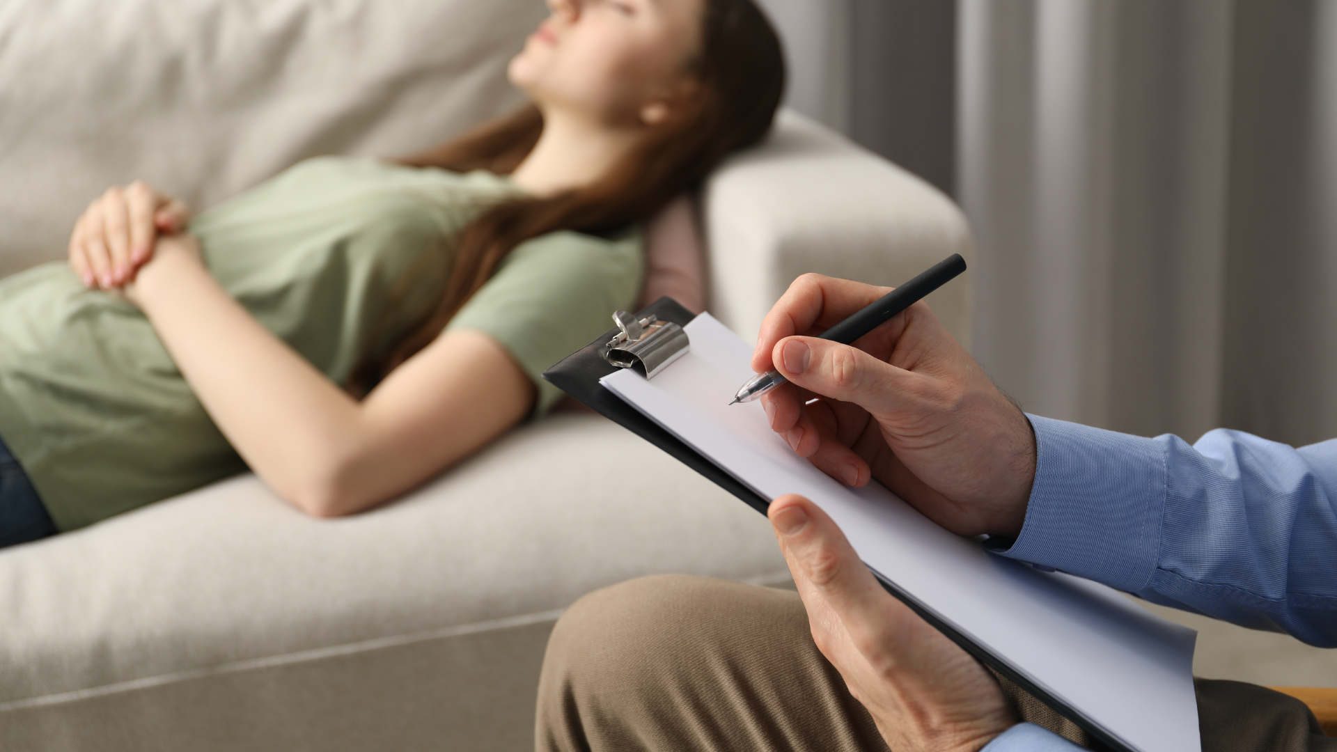 Therapist taking notes while a patient lies on a couch in a counseling session