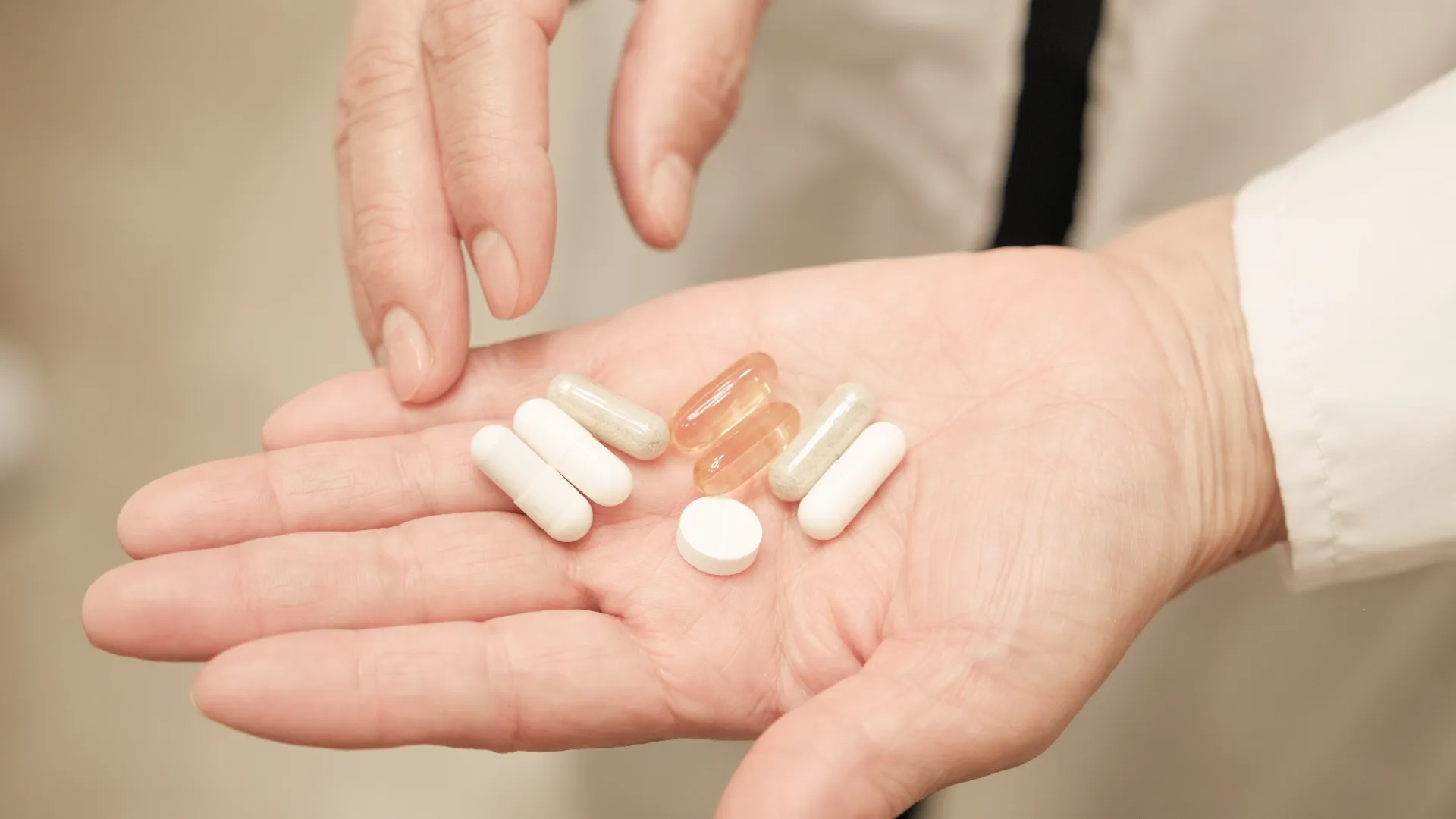 Open palm holding assorted pills while a finger points to them