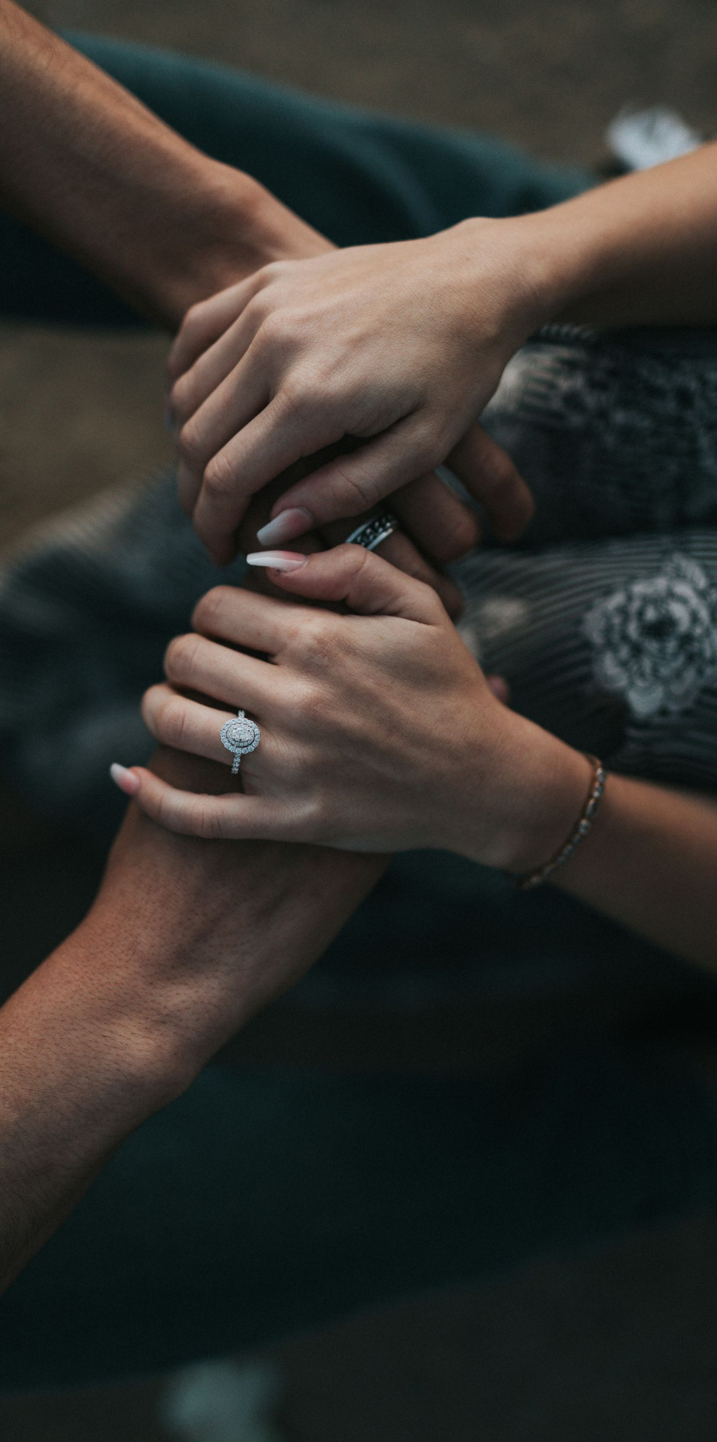 Several hands stacked together in a supportive gesture on a dark background