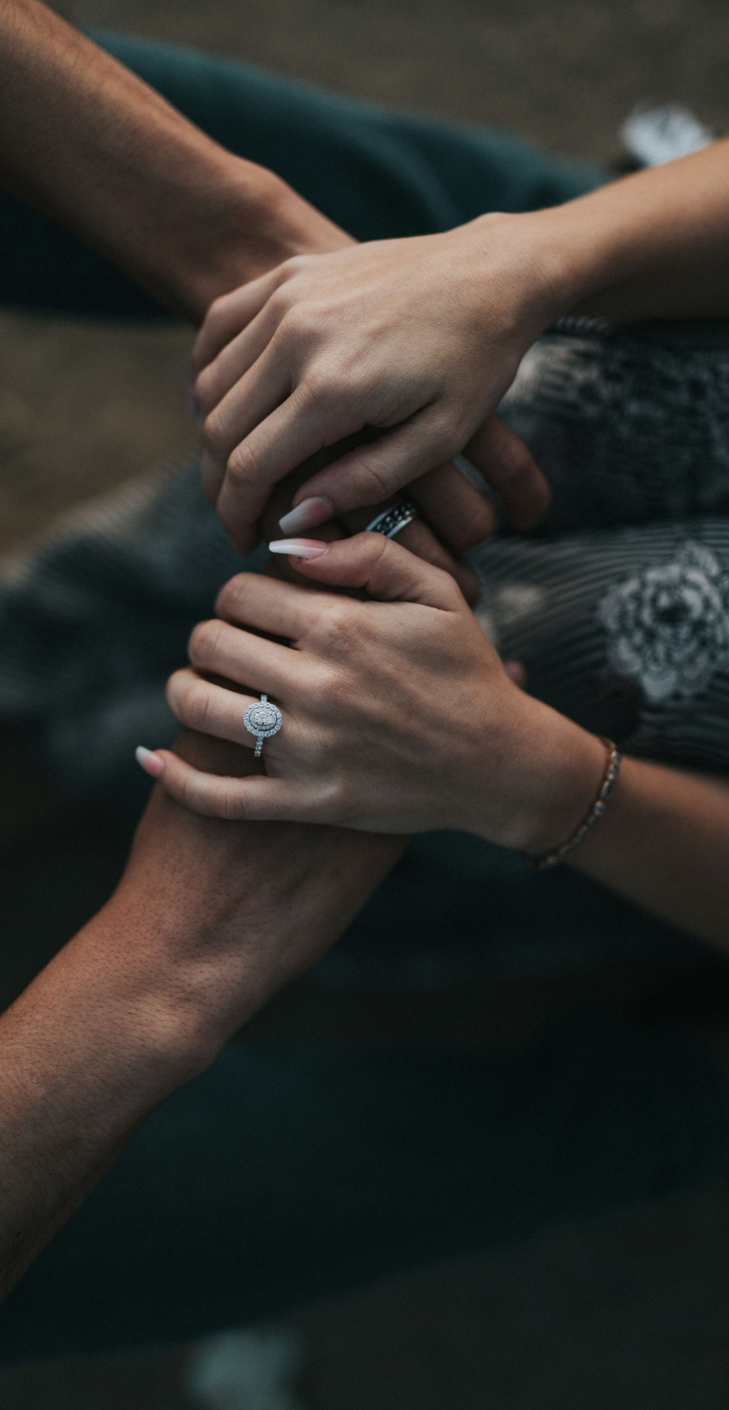 Several hands stacked together in a supportive gesture on a dark background