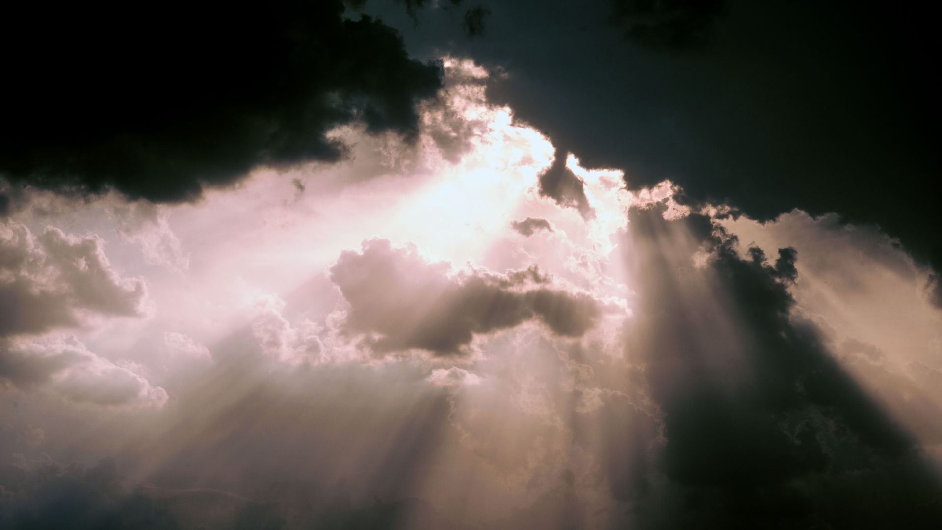 Sunbeams breaking through dark clouds in a dramatic sky