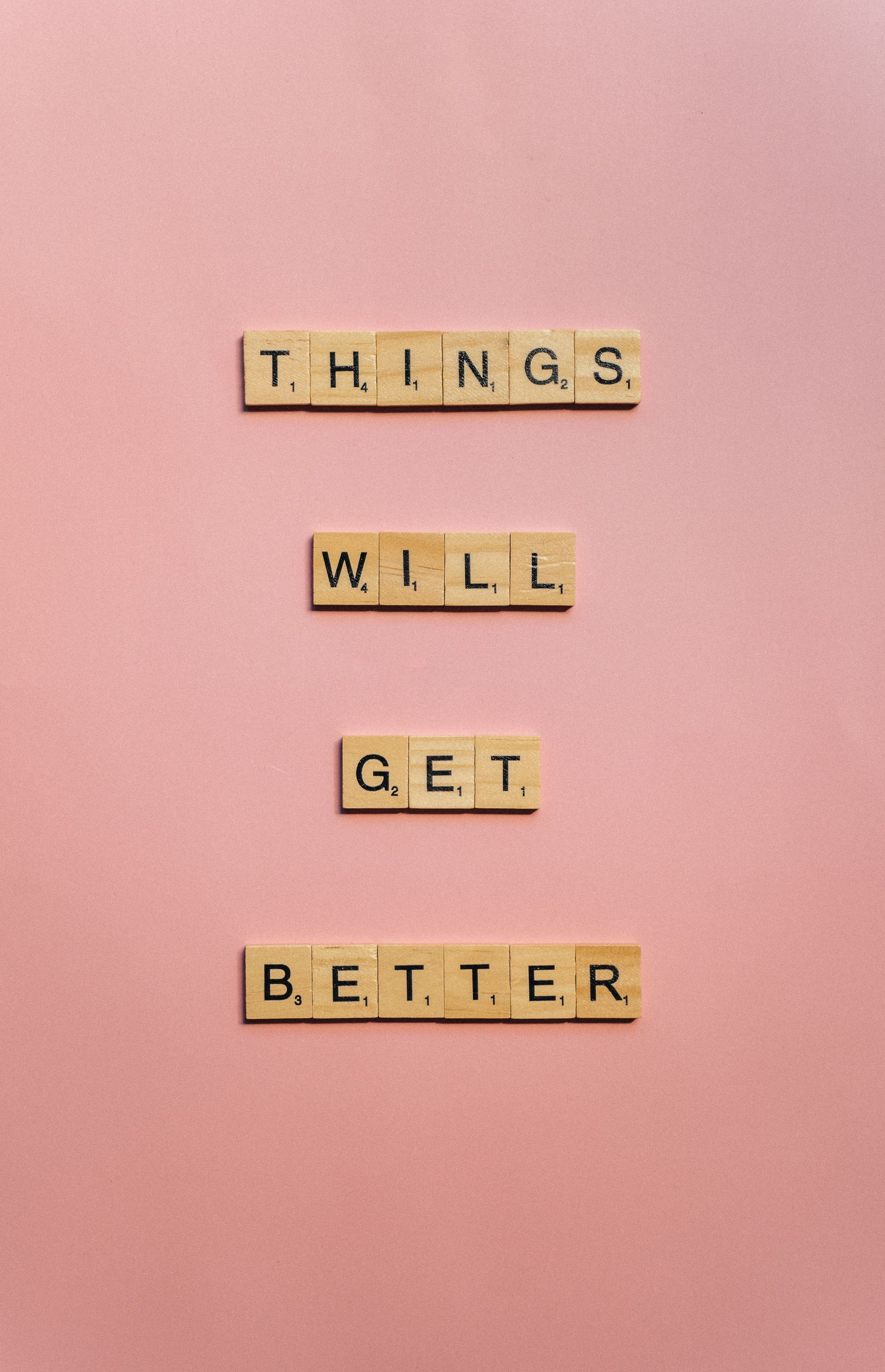 Wooden letter tiles on a pink background spell “THINGS WILL GET BETTER.”