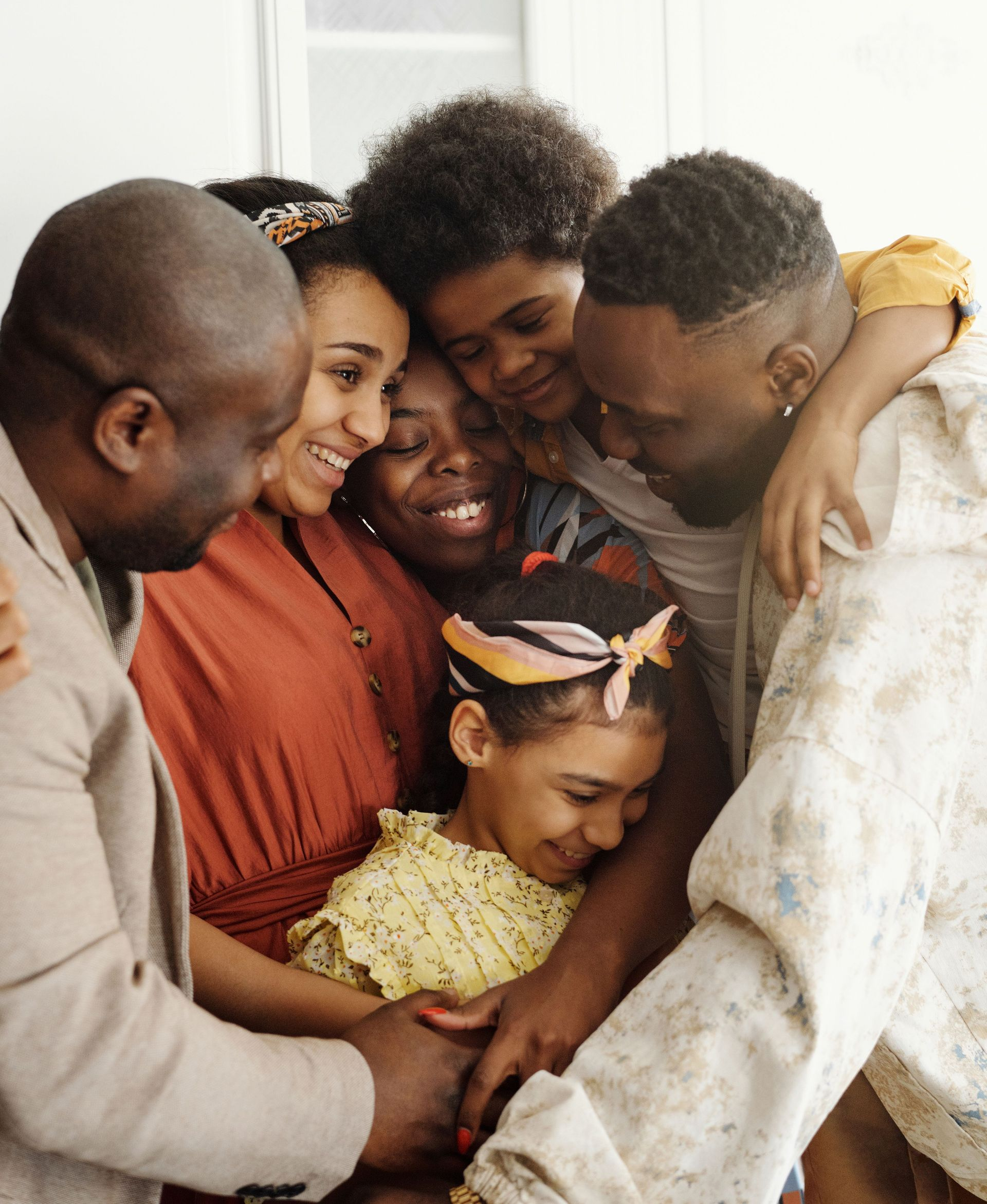 Five people huddle together in a warm group hug indoors.