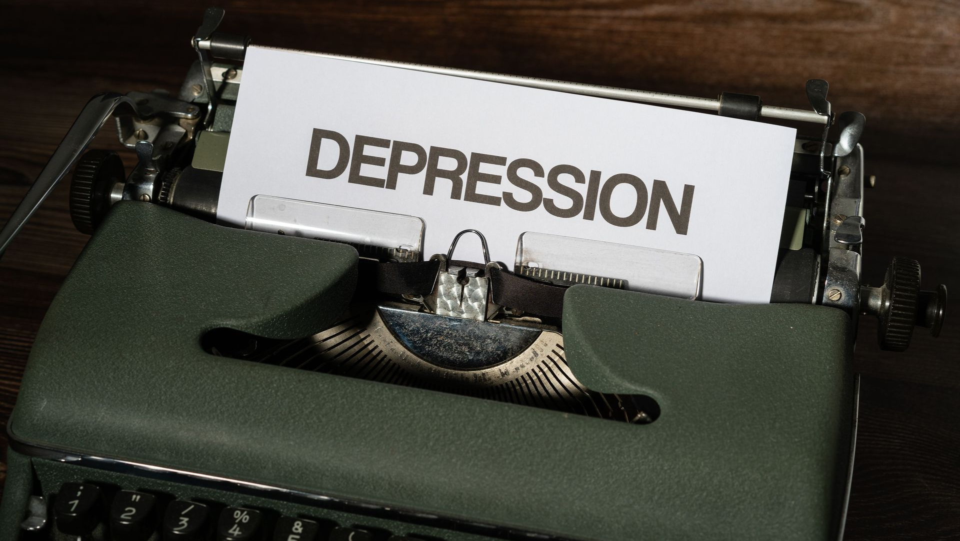 Vintage typewriter with a paper reading “DEPRESSION” in the carriage.