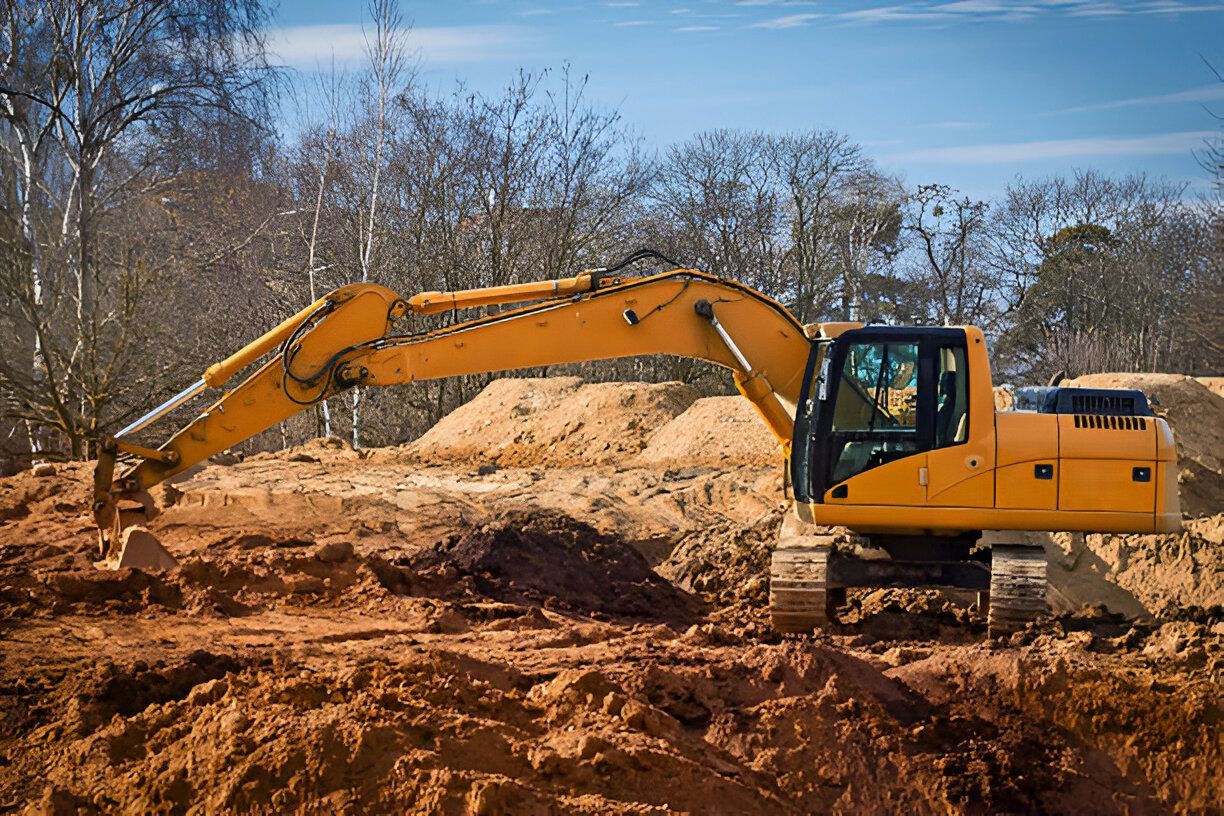 A yellow excavator is digging a hole in the dirt on a construction site.