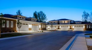 A row of houses are sitting next to each other on a residential street at night.