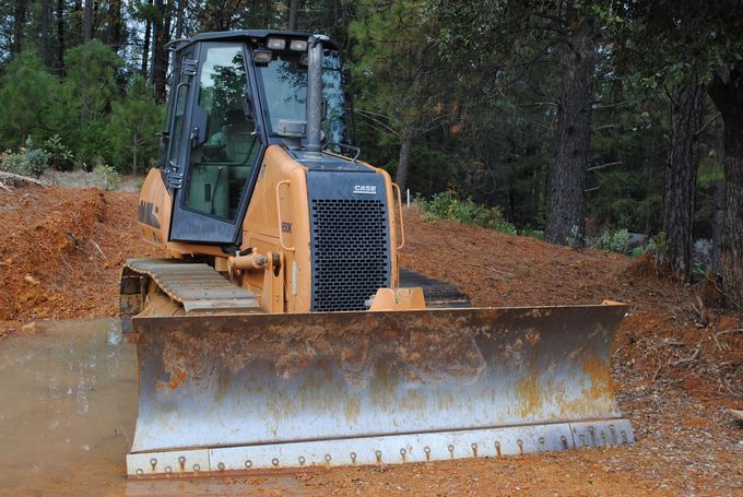 A bulldozer is driving through a muddy field.