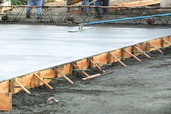 A concrete floor is being poured on a construction site.