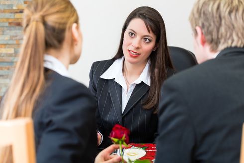 Eine Frau im Anzug hält eine Rose vor einer Gruppe von Menschen