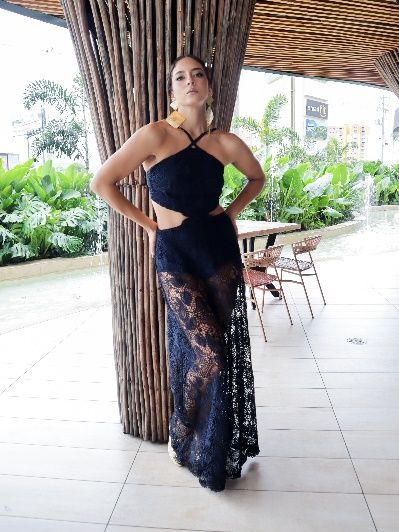 Una mujer con un vestido negro está de pie junto a un árbol.