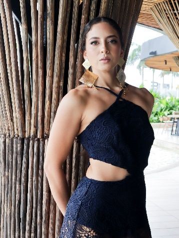 Una mujer con un vestido negro está de pie junto a un árbol.