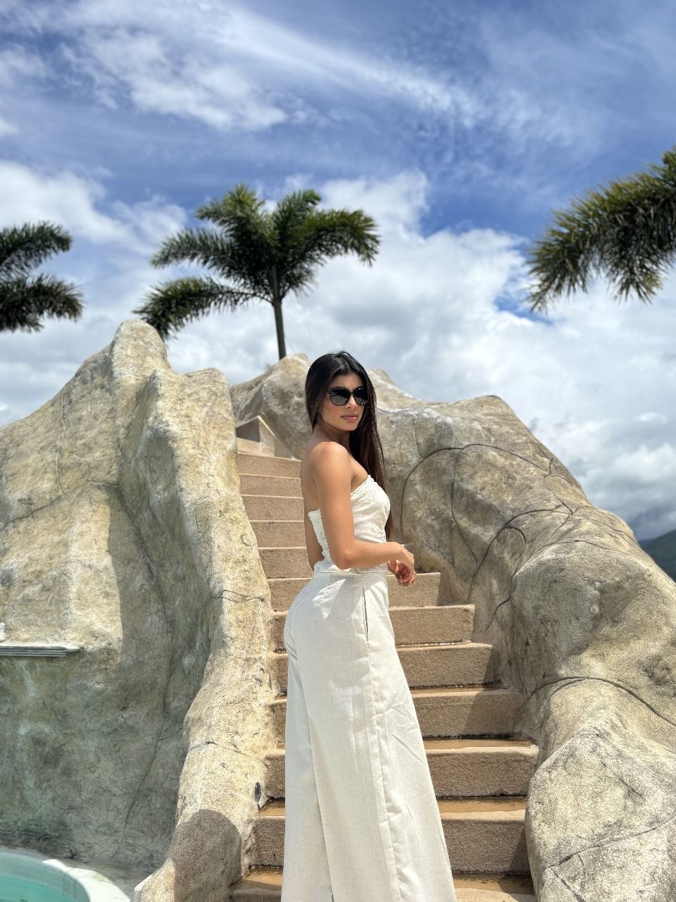 Una mujer con un vestido blanco está parada en un conjunto de escaleras.