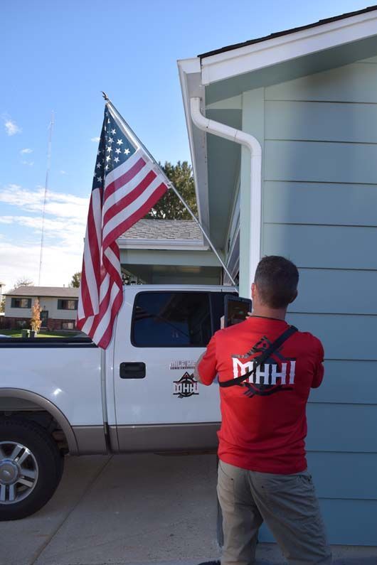A man in a red shirt that says mhhhi is standing in front of a truck