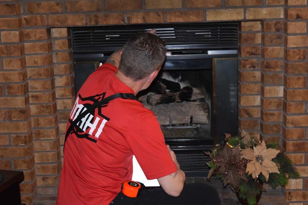 A man wearing a red shirt that says utah is working on a fireplace