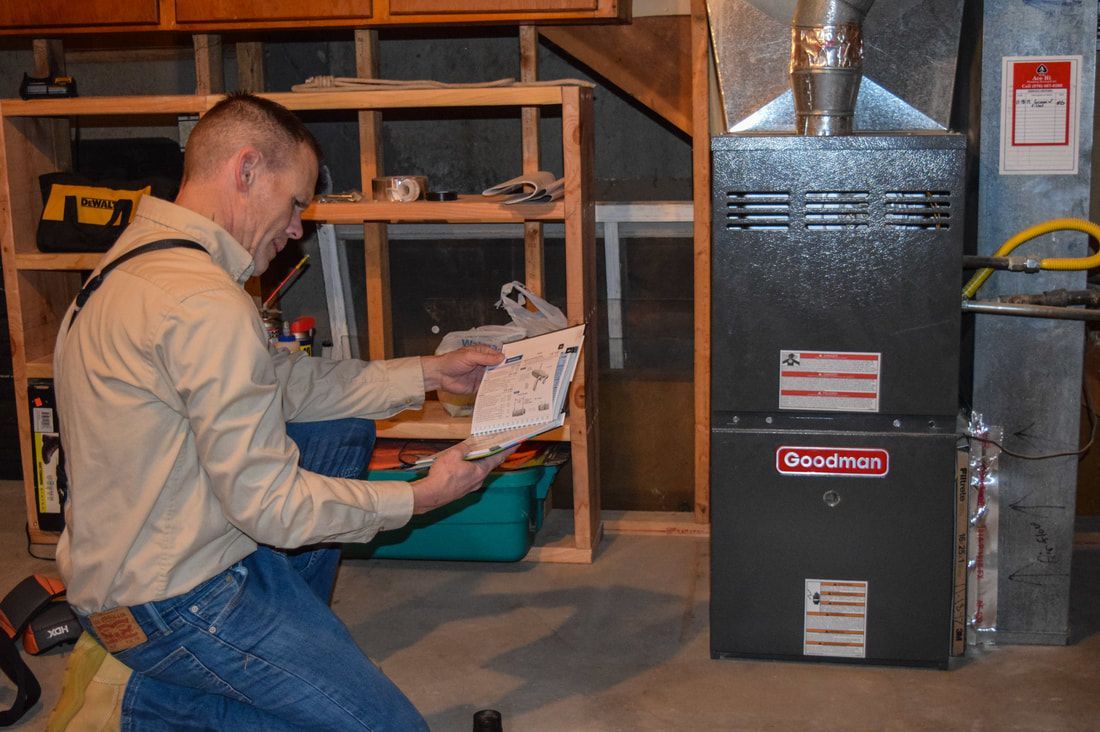 A man is kneeling down in front of a geothermal heater
