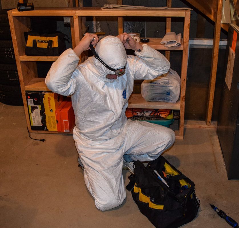 A man in a white protective suit is kneeling down