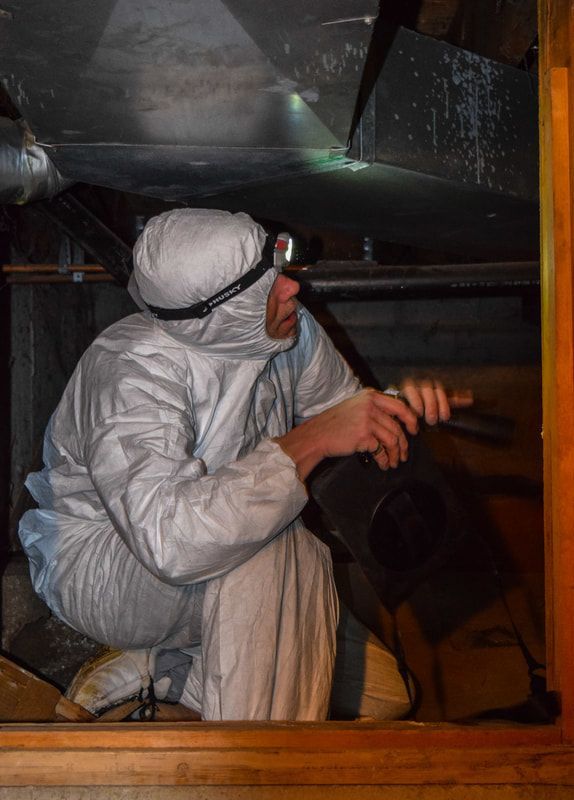 A man in a protective suit is kneeling down in a room.
