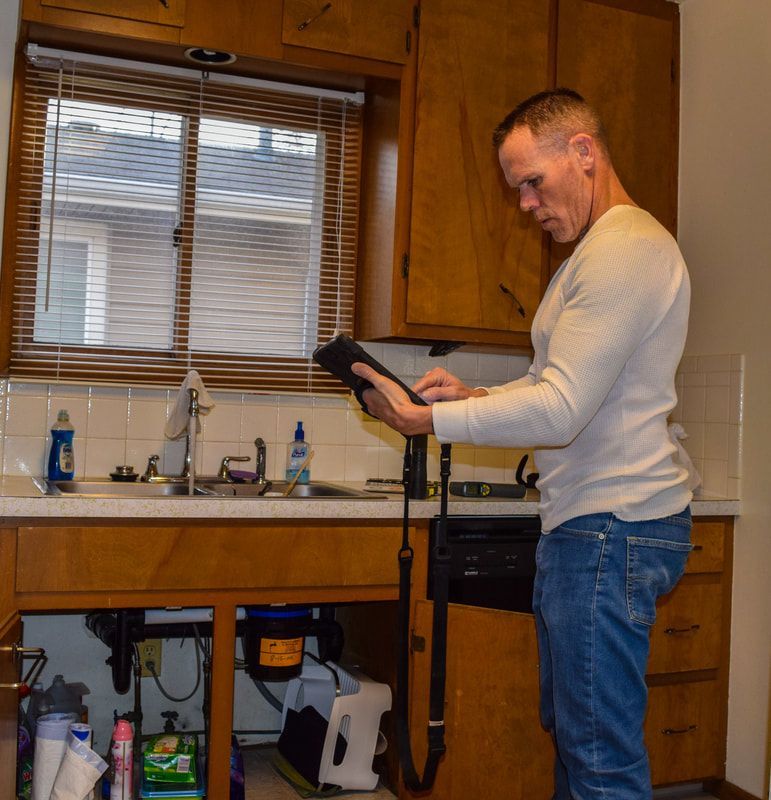 A man standing in a kitchen looking at a tablet